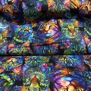 May include: A fabric with a repeating pattern of colorful cat faces. The cats are depicted in a stained-glass style, with vibrant blues, oranges, greens, and purples. The background is black, making the cat faces stand out.