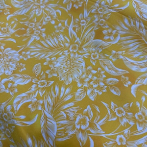 May include: Yellow fabric with a white floral pattern featuring tropical leaves and flowers. The design includes detailed botanical illustrations, creating a vibrant and eye-catching textile. The fabric's bright color and intricate design suggest a tropical theme.