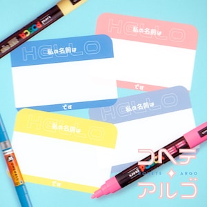 May include: Four colorful name tags with the text "Hello, my name is" in Japanese. The tags are blue, yellow, pink, and light blue. The text is in white. The tags are on a light blue background.