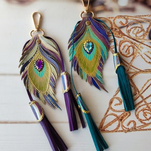 May include: Two leather peacock feather keychains with gold accents and jeweled eyes. Each keychain has a purple or teal tassel.