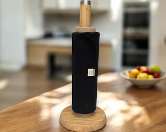 May include: A bamboo paper towel holder with a black cloth paper towel roll. The holder has a silver top and a wooden base.