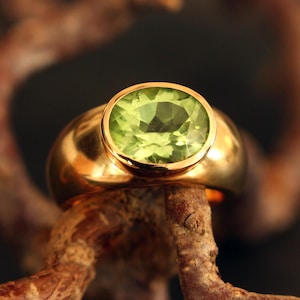 Handgeschmiedeter Solitärring aus massivem 750 Gelbgold (18 Karat) mit einem facettierten Peridot. Der Edelstein zeigt eine seltene, tiefe turmalingrüne Nuance und ruht auf einem natürlichen Zweig.