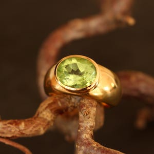 Handgeschmiedeter Solitärring aus massivem 750 Gelbgold (18 Karat) mit einem facettierten Peridot. Der Edelstein zeigt eine seltene, tiefe turmalingrüne Nuance und ruht auf einem natürlichen Zweig.
