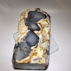 May include: A large, irregularly shaped piece of agate with a gray, white, and brown color pattern. The agate has a smooth, polished surface.