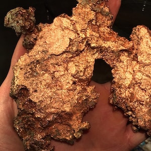 Puede incluir: Un gran trozo de mineral de cobre de forma irregular con una superficie rugosa y texturizada. El cobre tiene un color marr&oacute;n rojizo y est&aacute; cubierto por una capa de oxidaci&oacute;n.