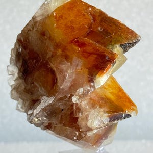 May include: A cluster of orange calcite crystals on a clear acrylic stand. The crystals are translucent and have a glassy lustre.