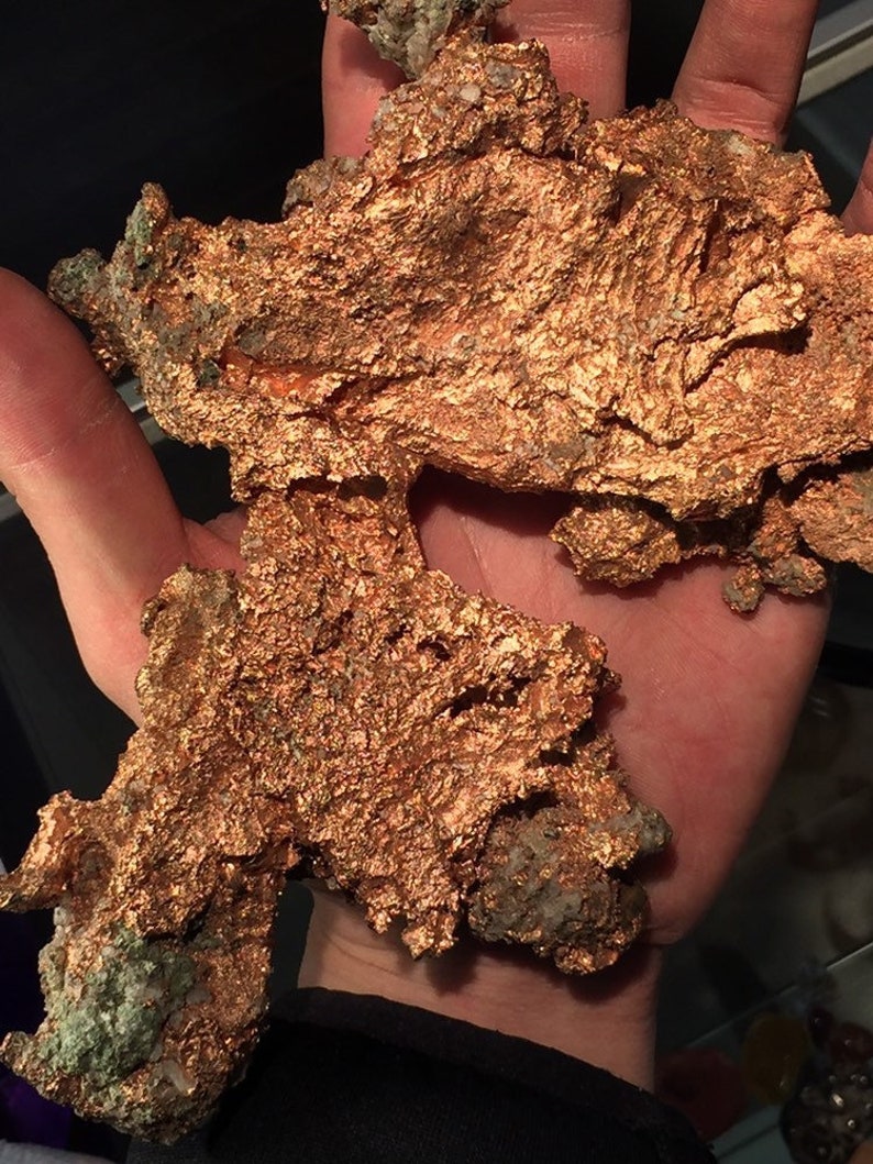 Puede incluir: Un gran trozo de mineral de cobre de forma irregular con una superficie rugosa y texturizada. El mineral es de color marr&oacute;n rojizo y tiene un brillo met&aacute;lico.