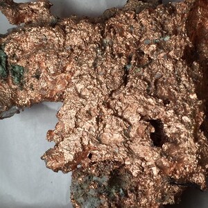 Puede incluir: Un gran trozo de mineral de cobre en bruto de color marr&oacute;n rojizo. El mineral tiene una superficie texturizada con muchas formas peque&ntilde;as e irregulares.