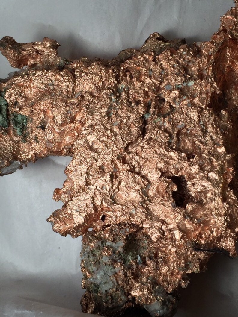 Puede incluir: Un gran trozo de mineral de cobre en bruto de color marr&oacute;n rojizo. El mineral tiene una superficie texturizada con muchas formas peque&ntilde;as e irregulares.