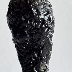Black tektite meteorite over rock space original unique stone rare old rough