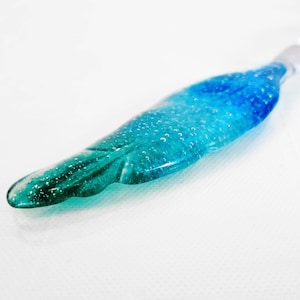 A feather made of glass in blue tones.