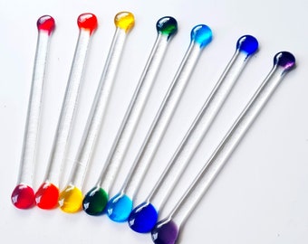 May include: Eight glass stirring sticks with colorful glass tips. The tips are red, orange, yellow, green, blue, light blue, purple, and dark blue.