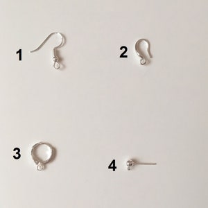 May include: Four silver jewelry findings, numbered 1 through 4. Finding 1 is a silver earring hook, finding 2 is a silver jump ring, finding 3 is a silver jump ring, and finding 4 is a silver bead with a loop.