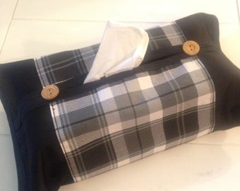May include: A rectangular tissue box cover with a black and white plaid pattern on the front and sides. The ends are solid black, and it has two wooden buttons. White tissues are visible.