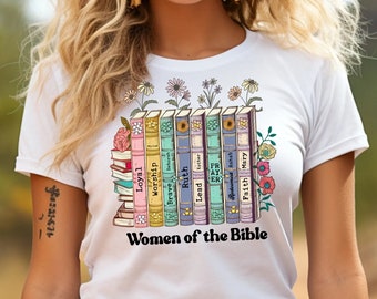 May include: White t-shirt with a graphic of a stack of books with words like "Loyal", "Worship", "Brave", "Ruth", "Lead", "Faith", and "Mary" on the spines. The text "Women of the Bible" is below the books.