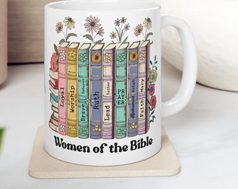 May include: White ceramic mug with a colorful illustration of books with words like "Loyal", "Worship", "Brave", "Ruth", "Lead", "Esther", "Pray", "Redeemed Rahab", "Faith", and "Mary" on the spines. The text "Women of the Bible" is printed below the books.