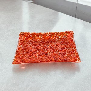 May include: Orange glass serving tray with a textured surface. The tray is made of clear glass with small orange bubbles throughout.