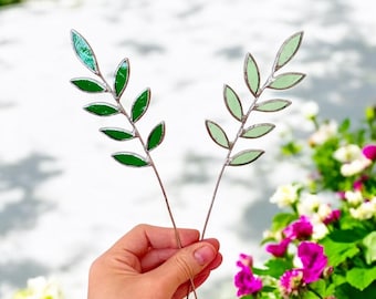 May include: Two stained glass leaf sprigs with green and light green leaves on silver wire stems.