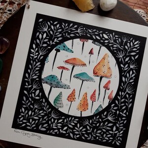 May include: A black and white illustration of a circle filled with colorful mushrooms. The circle is surrounded by a black border with white floral designs. The text "Nina Gypsy Burning" is in the bottom left corner.