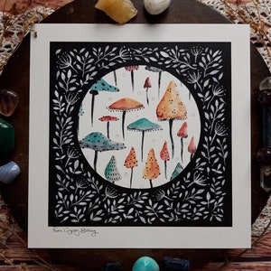 May include: A black and white illustration of a circle filled with colorful mushrooms. The mushrooms are various shades of orange, red, green, and blue. The circle is surrounded by a black frame with white leaves and branches.