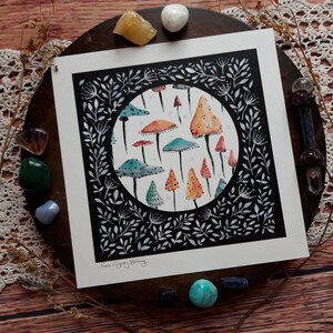 May include: A black and white illustration of a circle filled with colorful mushrooms. The mushrooms are various shades of orange, red, blue, and green. The circle is surrounded by a black border with white floral designs.