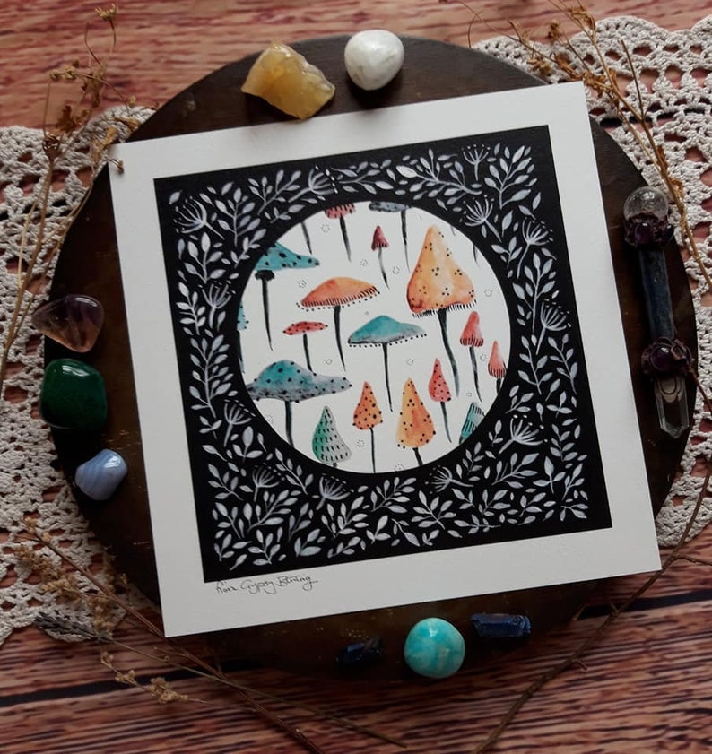 May include: A black and white illustration of a circle filled with colorful mushrooms. The mushrooms are various shades of orange, red, blue, and green. The circle is surrounded by a black border with white floral designs.