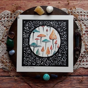 May include: A black and white illustration of a circle filled with colorful mushrooms. The mushrooms are various shades of orange, red, yellow, and blue. The circle is surrounded by a black border with white leaves and vines.