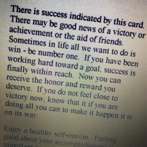 May include: A printed card or page titled SIX OF WANDS in bold black text. The text describes the card's meaning, stating there is success indicated, good news of a victory, achievement, or aid of friends. It mentions working hard toward a goal.