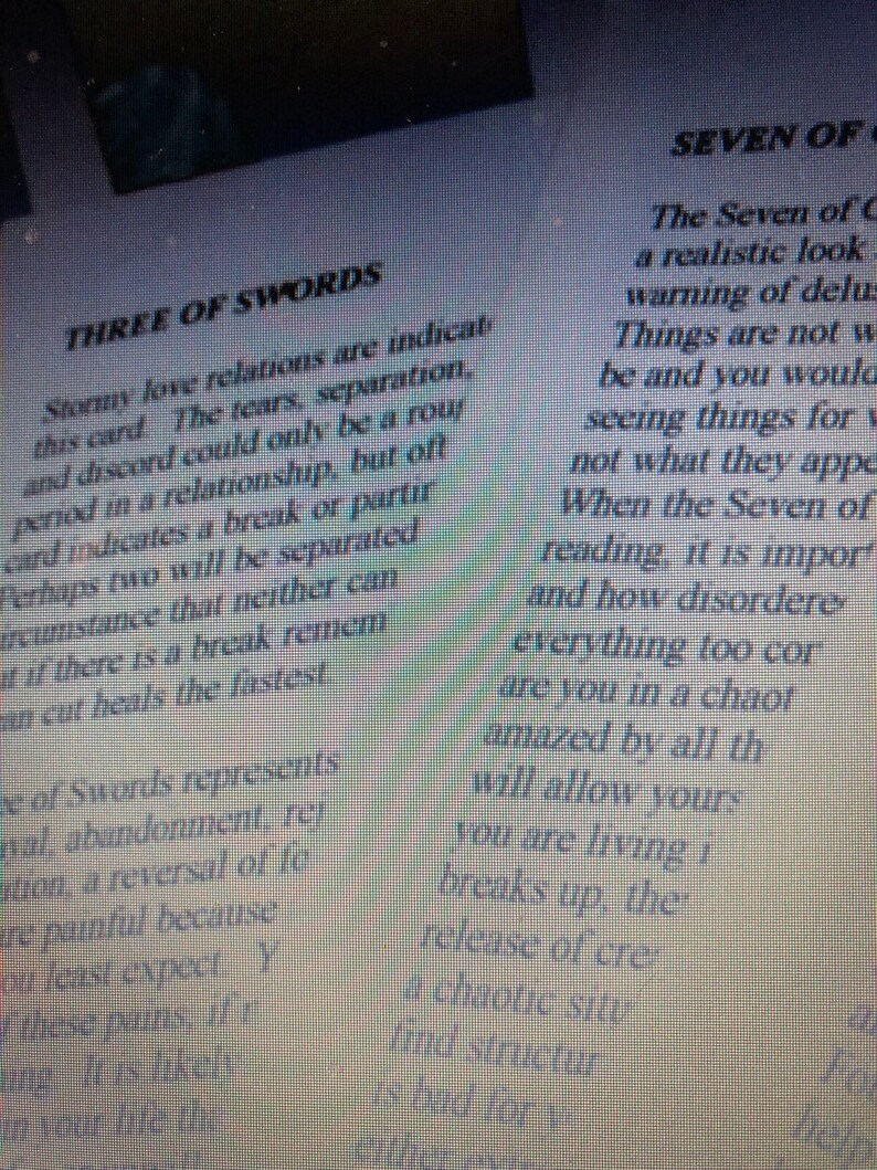May include: A printed page featuring text about tarot cards, specifically the Three of Swords and the Seven of Cups. The text describes the Three of Swords as indicating stormy love relations, tears, and separation, while the Seven of Cups text discusses delusions and things not being what they appear to be.