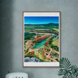 May include: A framed painting of a landscape with a river winding through a valley. The painting is in a modern style with bright colors and bold brushstrokes. The river is a vibrant blue, and the trees are a mix of green, orange, and red.