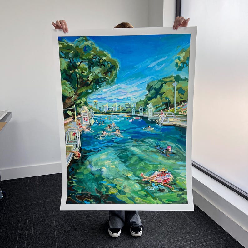K&ouml;nnte beinhalten: Ein gro&szlig;es, farbenfrohes Gem&auml;lde, das eine lebendige Szene im Freien darstellt. Das Kunstwerk zeigt ein Gew&auml;sser mit schwimmenden und treibenden Menschen. &Uuml;ppige gr&uuml;ne B&auml;ume und ein strahlend blauer Himmel mit Wolken umrahmen die Szene. Geb&auml;ude sind in der Ferne zu sehen.