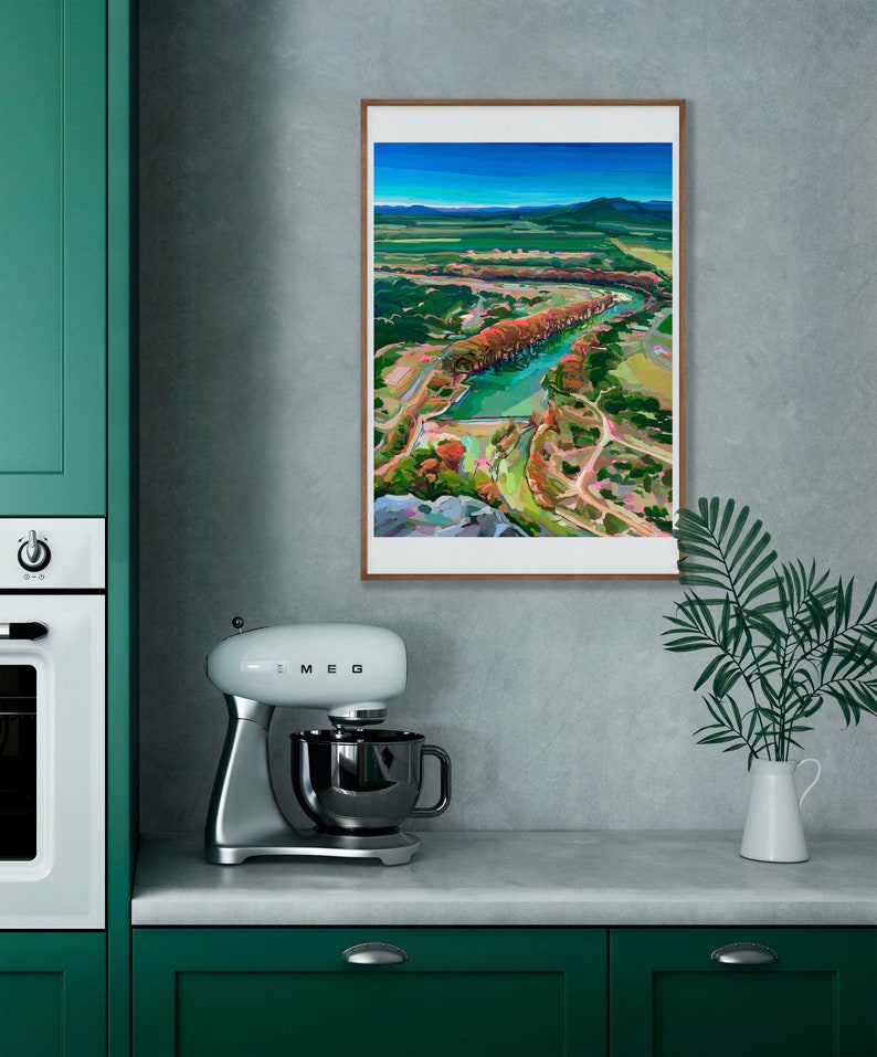 May include: A framed painting of a landscape with a river winding through a valley. The painting is in a modern style with bright colors and bold brushstrokes. The river is a vibrant blue, and the trees are a mix of green, orange, and red.