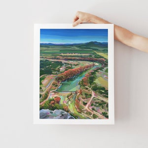May include: A painting of a river winding through a valley with a line of trees in the center of the river. The trees are a vibrant red and pink, while the surrounding landscape is a mix of green and brown.