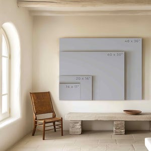 May include: A white wall with four different sized frames, each with a different measurement listed in inches. The frames are all empty and are hanging on the wall. A wooden chair and a stone bench are in the foreground.