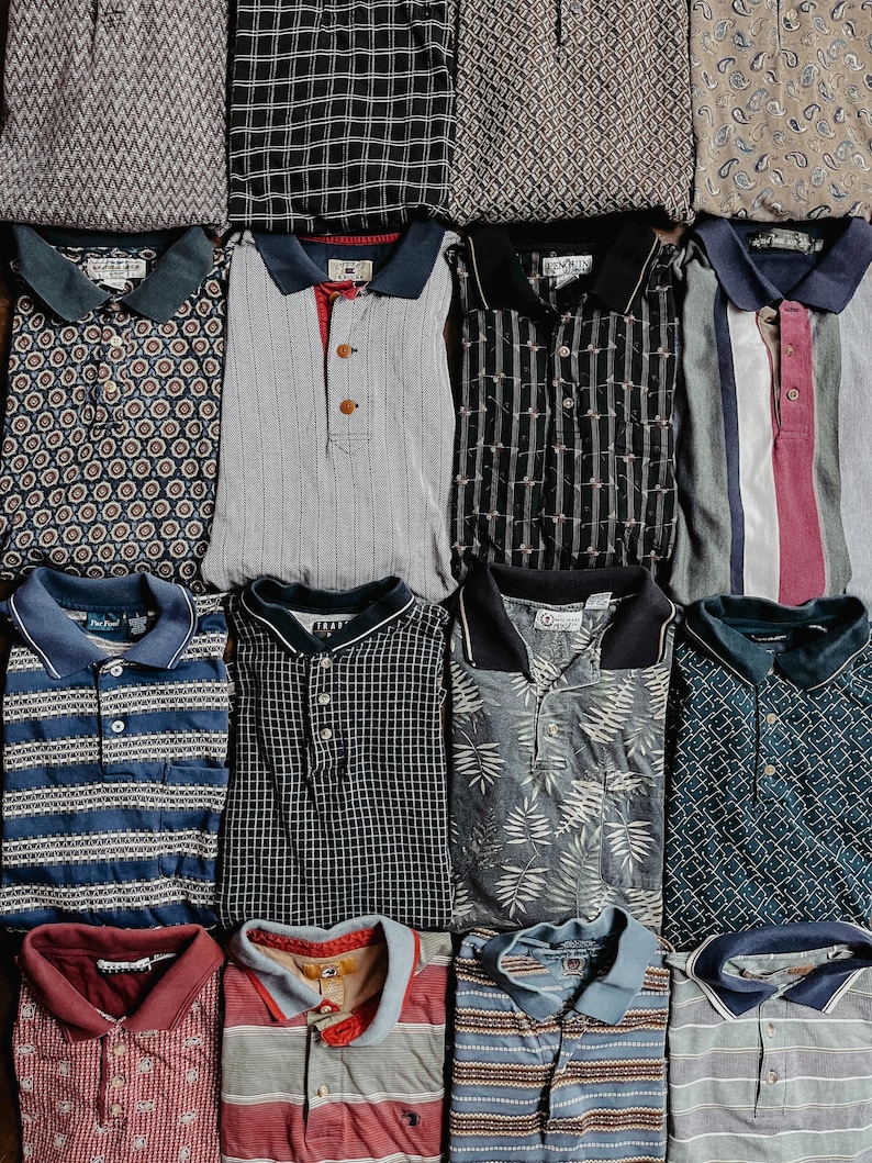 May include: A collection of twelve folded polo shirts arranged in a grid. The shirts feature various patterns including geometric shapes, stripes, plaid, paisley, and botanical prints in diverse colors such as blue, gray, black, red, and tan.