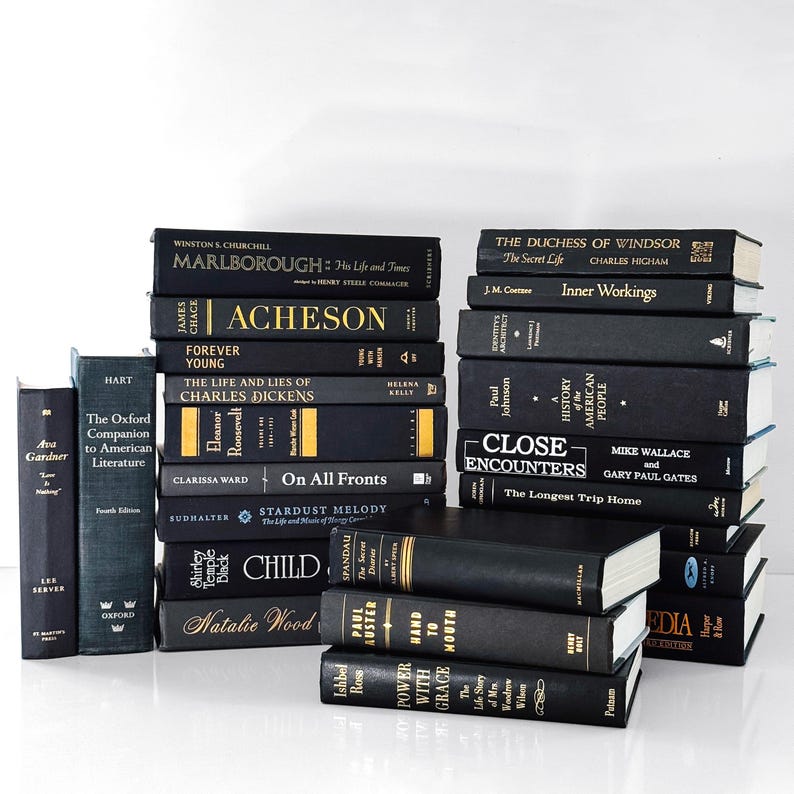 May include: A collection of hardcover books in various sizes and titles. The books are primarily black with gold or white lettering. Titles include "Marlborough," "Acheson," and "Close Encounters." The books are stacked and arranged on a white surface.