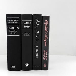 May include: Four hardcover books with black covers. The books are titled "Diaries Volume One 1939-1960", "Paris 1919", "Audrey Hepburn", and "Elizabeth & Margaret". The titles and author names are in white and pink.