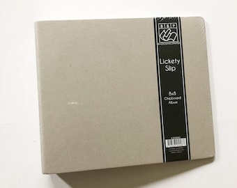 May include: A gray 8x8 chipboard album with the text "Lickety Slip" and "Bazill Basics Papers" on the front. The album is wrapped in plastic.