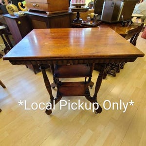 May include: A dark wood table with a scalloped edge and two shelves. The table has a distressed finish and is on wheels. The text "*Local Pickup Only*" is printed on the floor in front of the table.