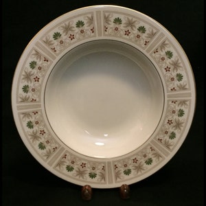 May include: A white ceramic soup bowl with a gold rim and a green and brown floral pattern.