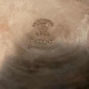 May include: Close-up of a ceramic object with a light brown interior and a darker rim. The centre features embossed text that reads "KEYSTONE" above a logo and the words "PATENT PENDING".