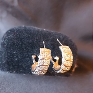 May include: A pair of silver hoop earrings with a row of small clear stones around the edge.