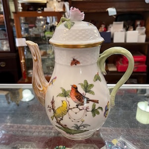 May include: A set of three ceramic mugs with a speckled, matte finish. Each mug features a different color: light blue, cream, and gray. The mugs have a simple, modern design with a rounded shape and a handle.