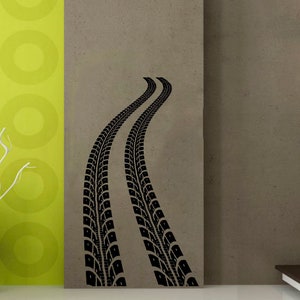 May include: Black tire track decal for a wall, showing two tire tracks leading upwards. The decal is on a light brown wall with a white light fixture in the upper right corner.