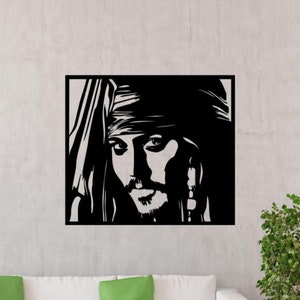 May include: Black and white wall art featuring a stylized portrait of a man with a bandana and goatee. The artwork is a square, framed piece, likely made of wood or metal, and mounted on a light gray wall. The image is a close-up of the man's face.
