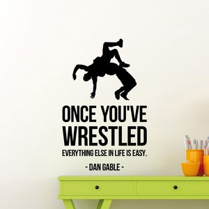 Puede incluir: Silueta en blanco y negro de dos luchadores en un agarre. La cita "Una vez que has luchado, todo lo demás en la vida es fácil. - Dan Gable -" está impresa debajo de la imagen.