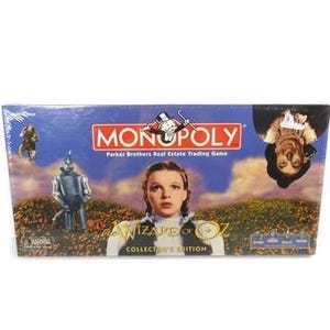 Könnte beinhalten: Monopoly-Spielbox mit Bildern aus Der Zauberer von Oz. Die Box hat das Monopoly-Logo, Bilder von Dorothy, dem Zinnmann und der Vogelscheuche. Die Worte "Collector's Edition" sind ebenfalls sichtbar.