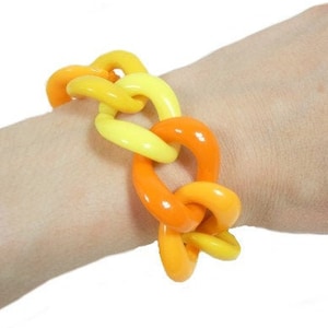 May include: A yellow and orange plastic chain link bracelet. The bracelet is made of large, chunky links.