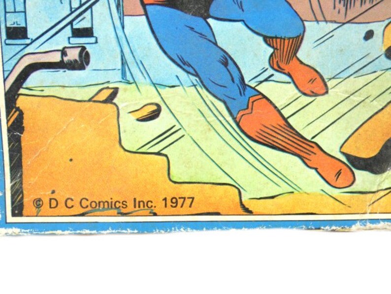 May include: A comic book cover featuring a superhero in a blue and red suit flying through the air. The cover is yellow and green with the text "DC Comics Inc. 1977".