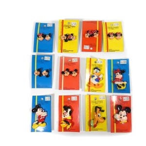 May include: A collection of Disney character pins on colorful backing cards. The pins feature Mickey Mouse, Minnie Mouse, Donald Duck, and Pluto. The cards are blue, yellow, and red.